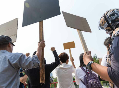 People holding blank protest signs outdoors.