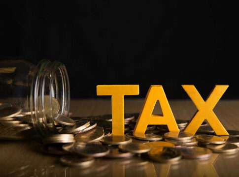 Jar of coins and TAX letters on table.