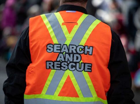 Search and rescue worker in an orange reflective vest seen from behind