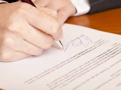 Hand signing a document with a pen