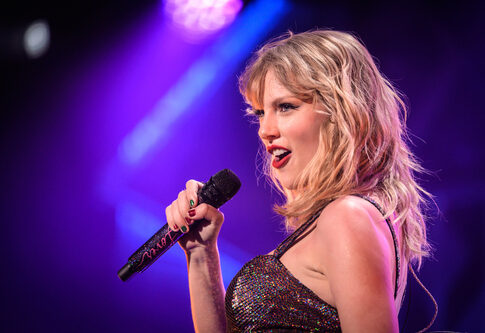 Singer performing on stage with a microphone under colorful lights