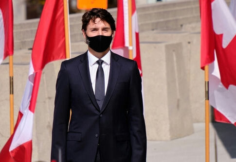 A man in a suit with Canadian flags in background.