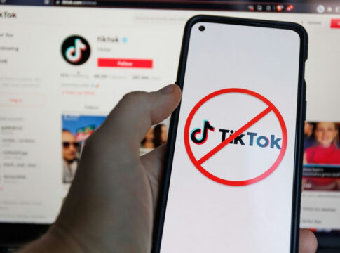Phone shows TikTok logo with prohibited symbol