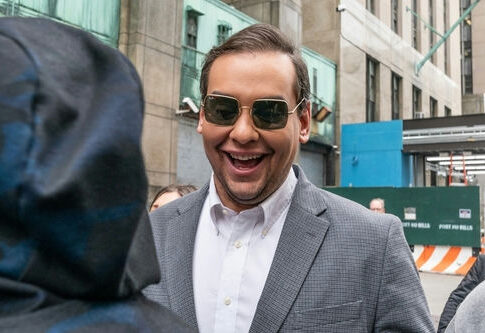 Man in sunglasses smiling on a city street.