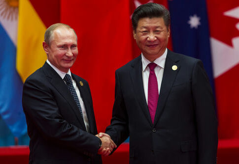 Vladimir Putin and Xi Jinping shaking hands at event.